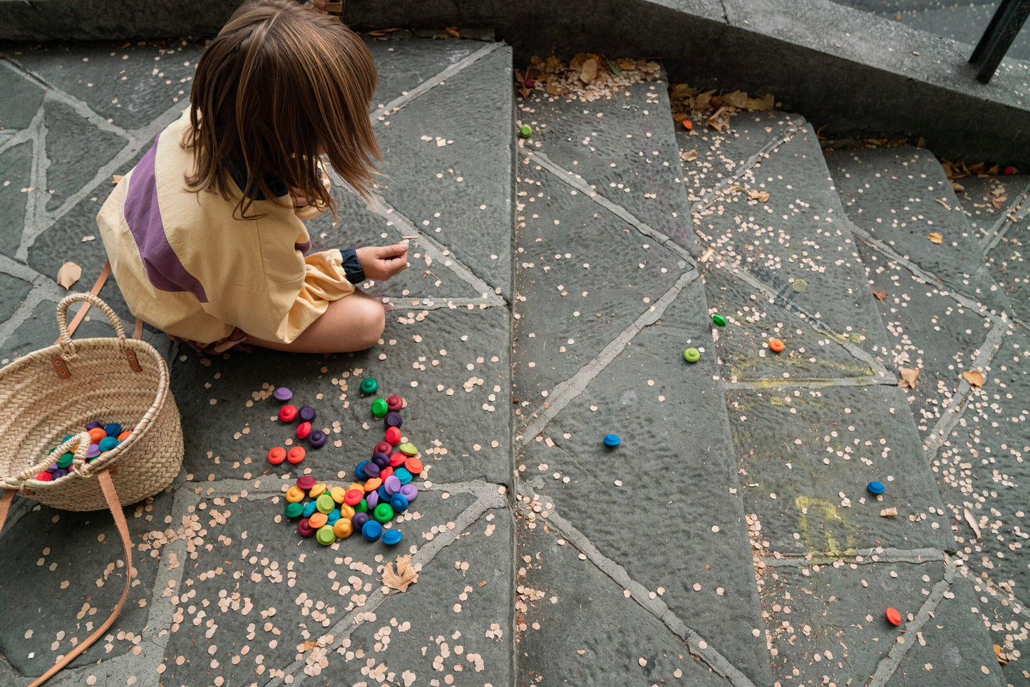 Child playing with colorful mandala on a stone pavement