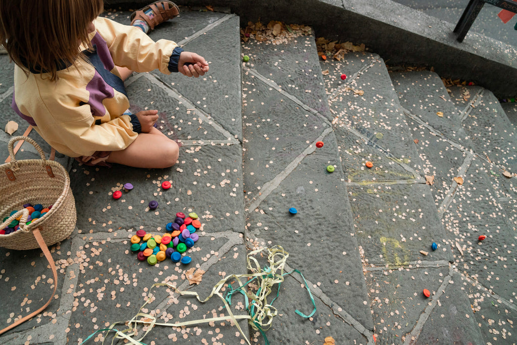 Child playing with colorful toys on a stone pavement