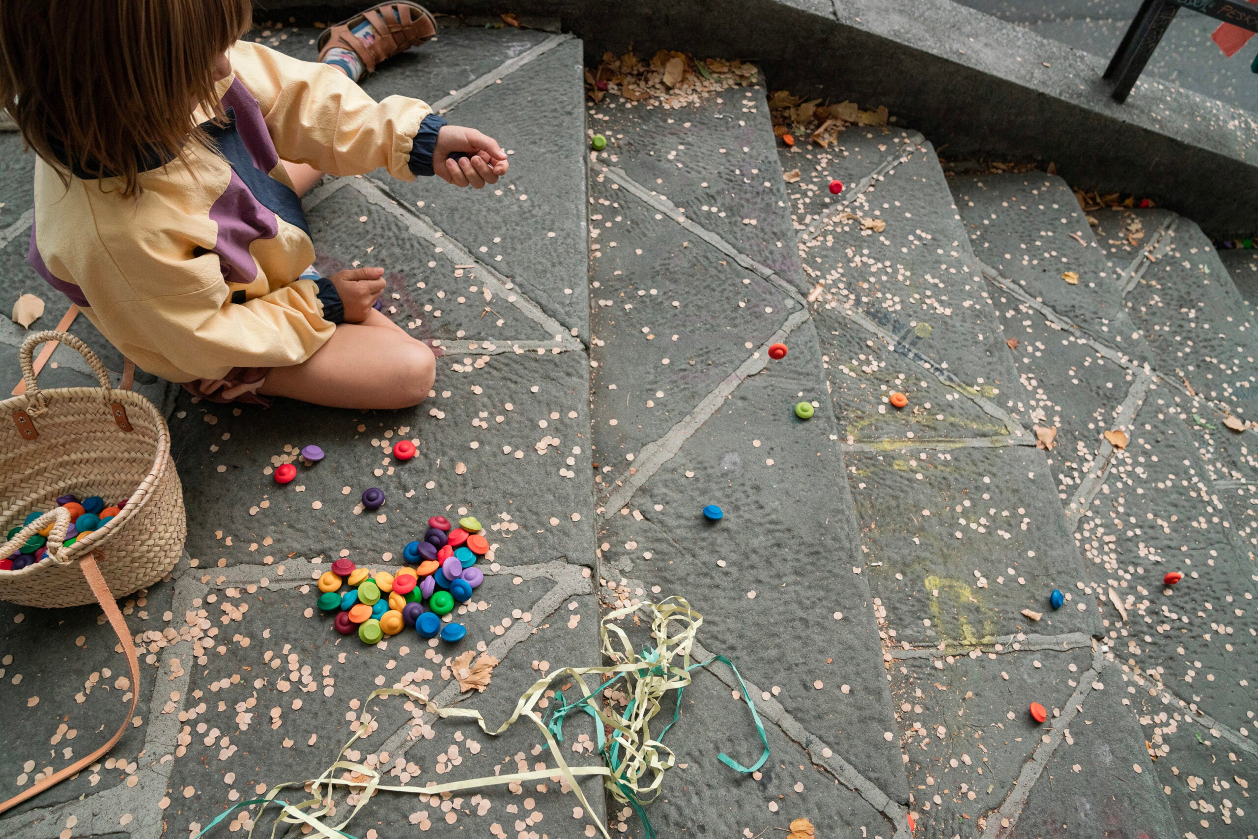 Child playing with colorful toys on a stone pavement