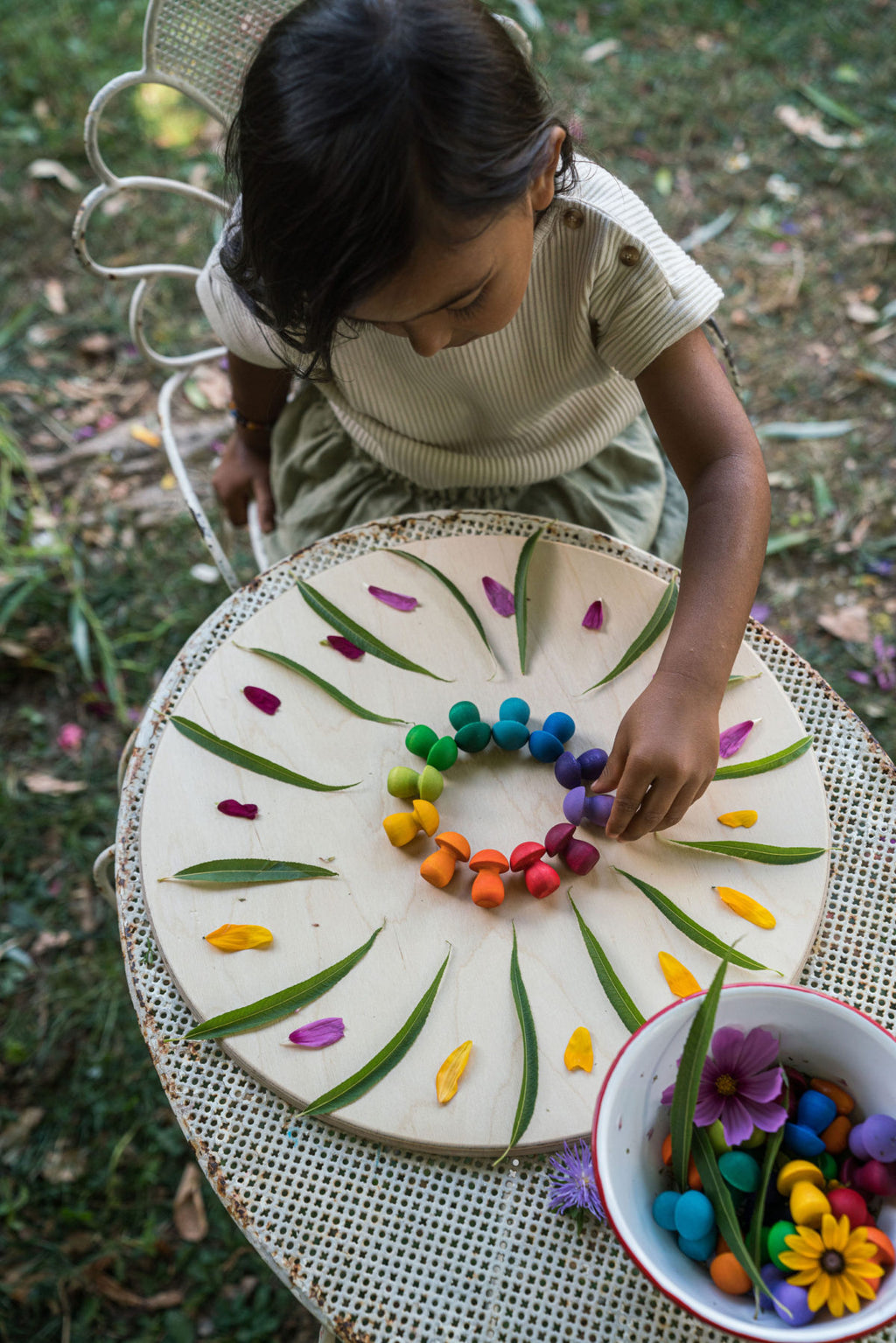 Child arranging colorful candies on a decorative plate outdoors