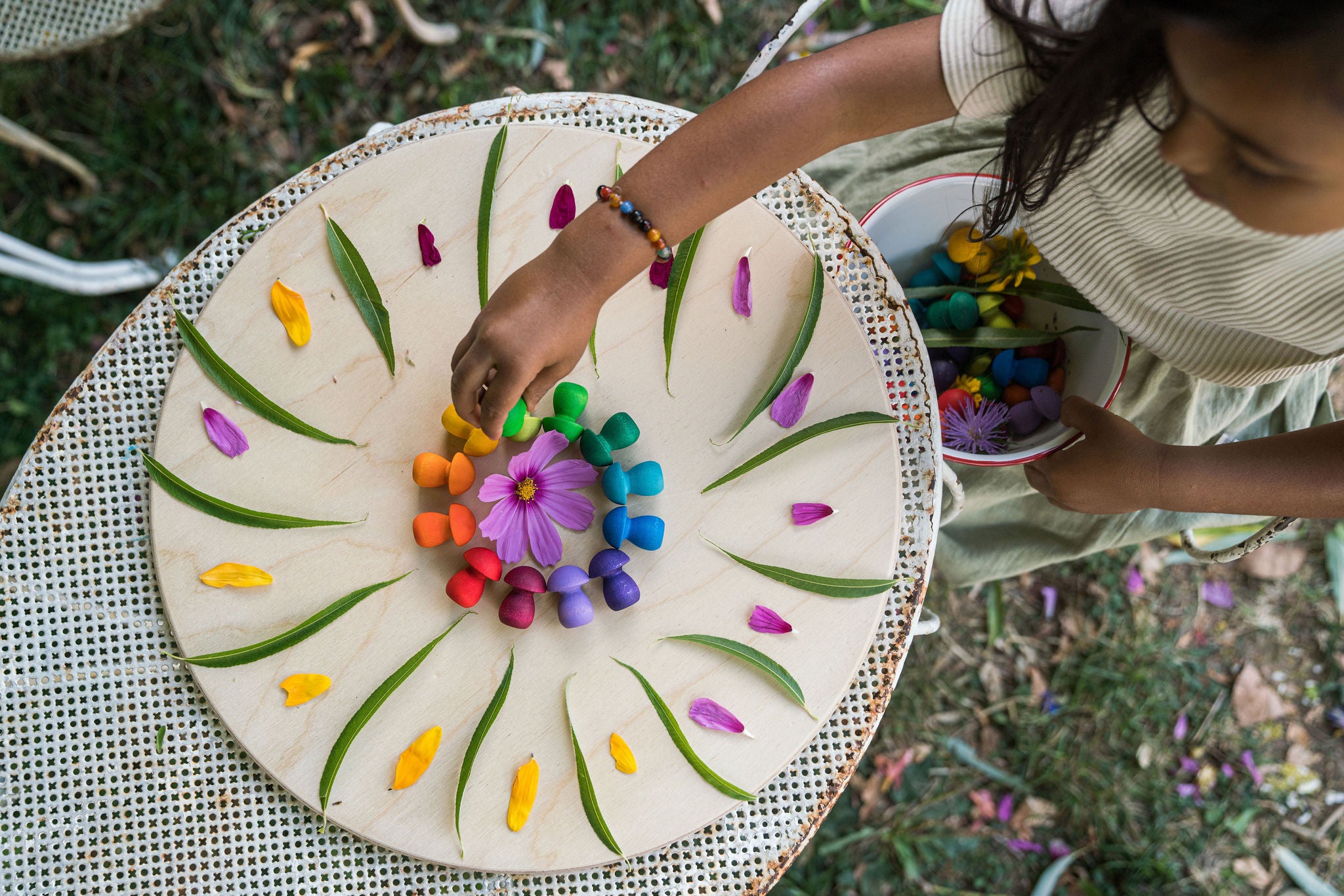 Child decorating a round white board with colorful flowers on a grassy background