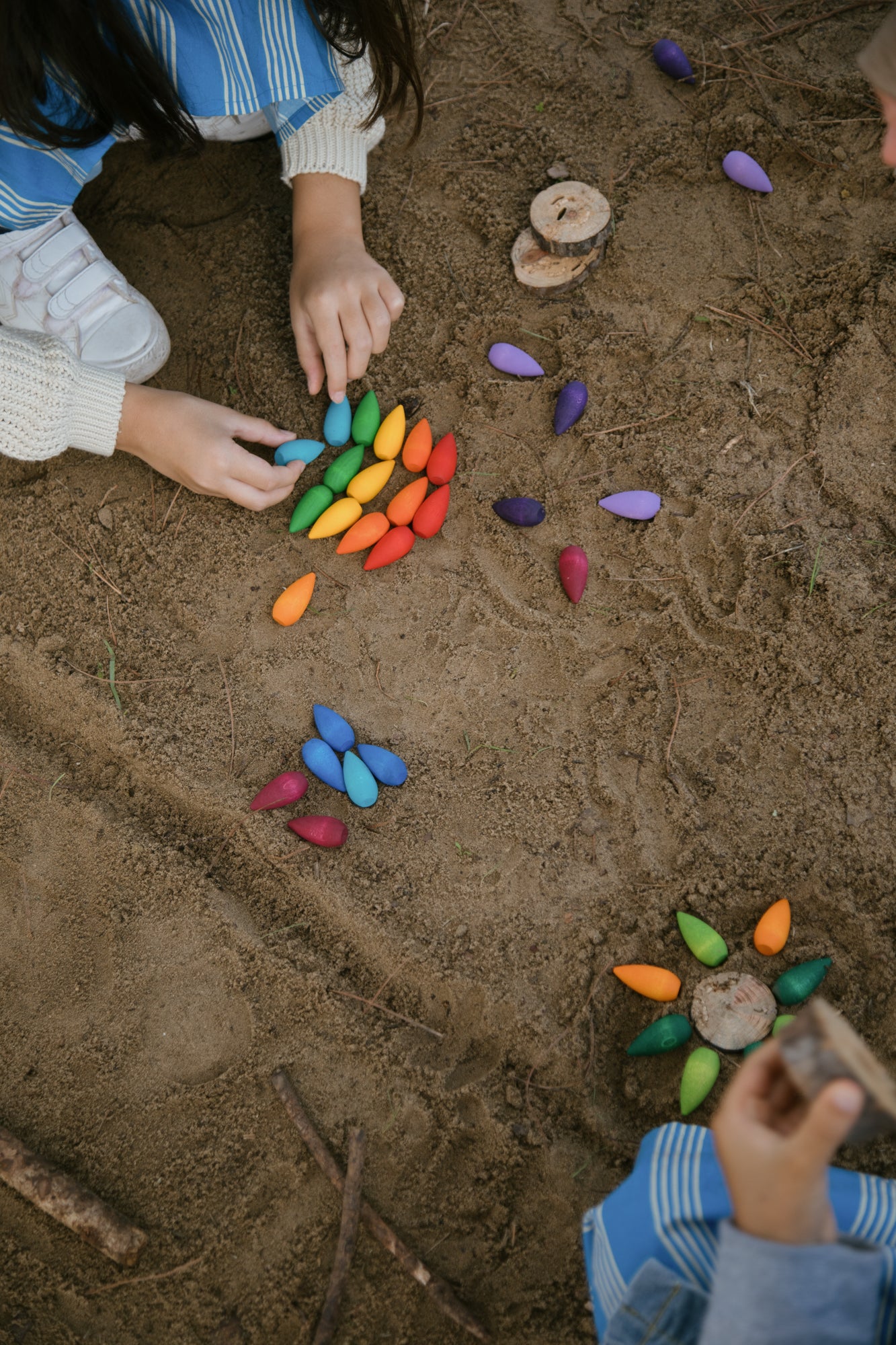 Children playing with colorful stones on a sandy surface