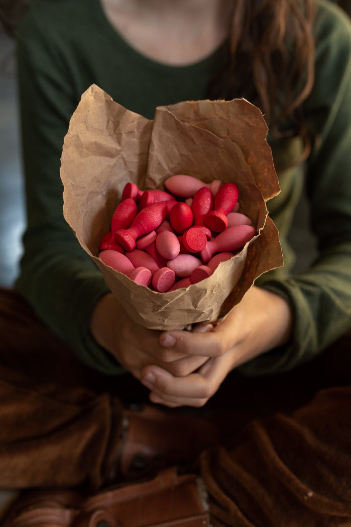 Person holding a bouquet of red and pink heart-shaped objects wrapped in brown paper.