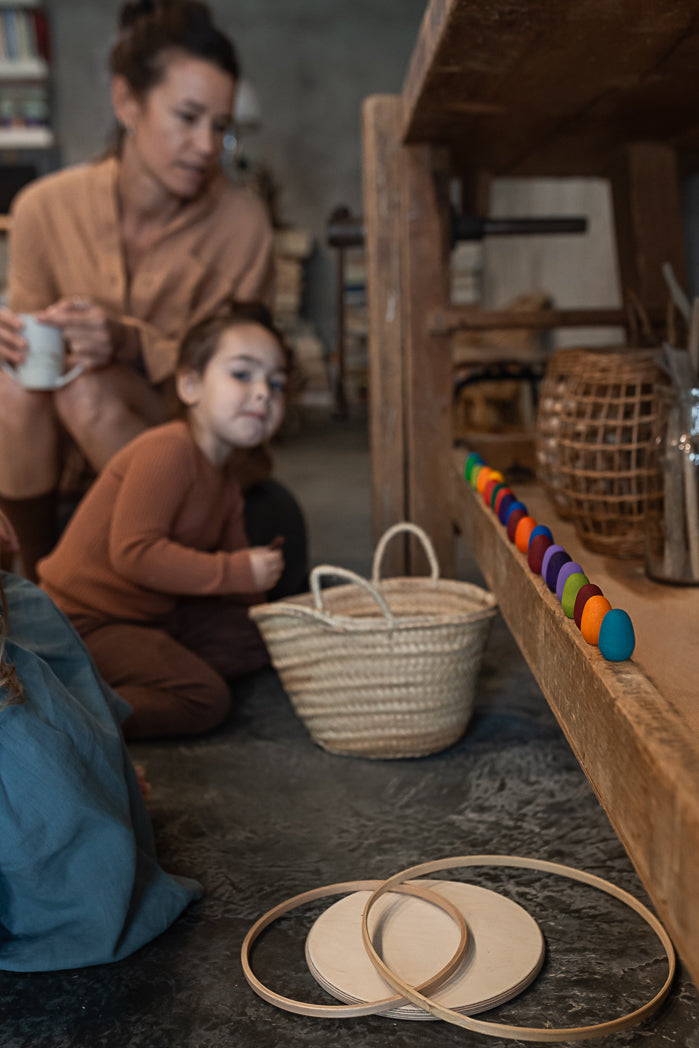 Woman and child sitting on the floor with toys and a basket in a home setting