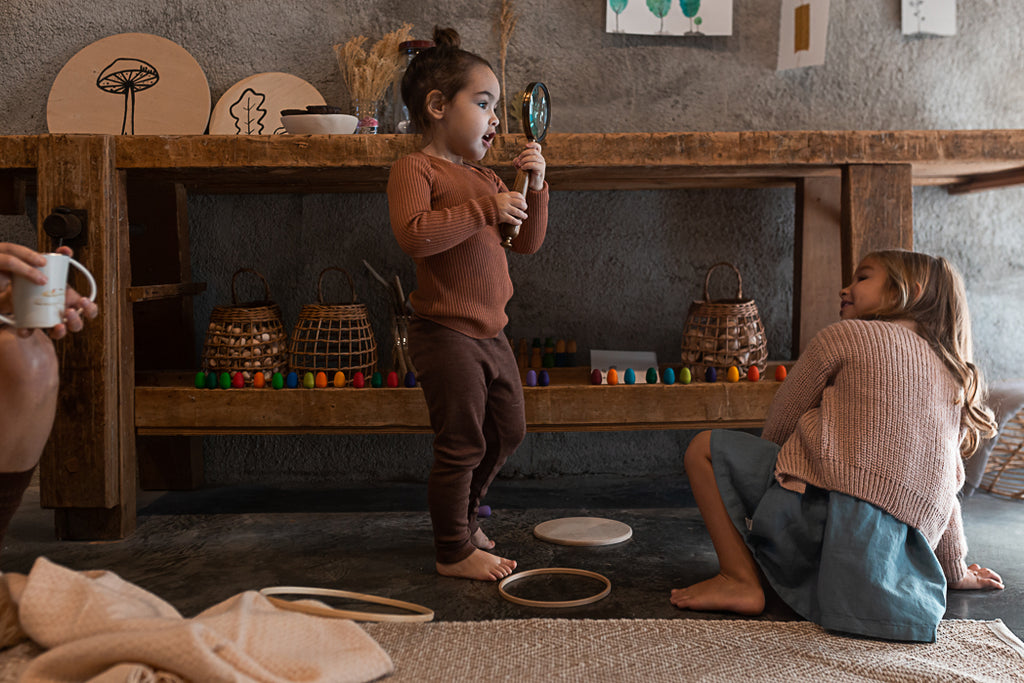Two children playing with toys on a wooden floor in a room with a rustic decor.