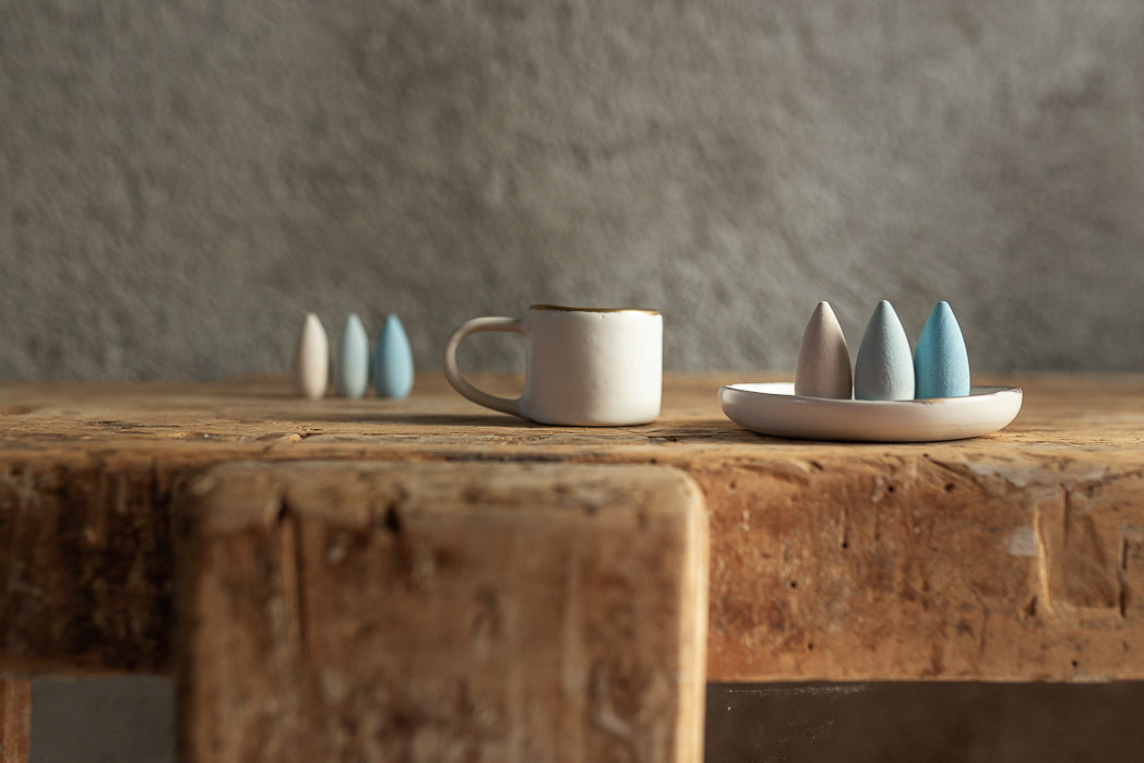 Ceramic mug and small decorative items on a wooden table with a neutral background