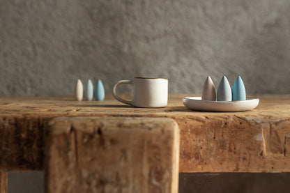 Ceramic mug and small decorative items on a wooden table with a neutral background