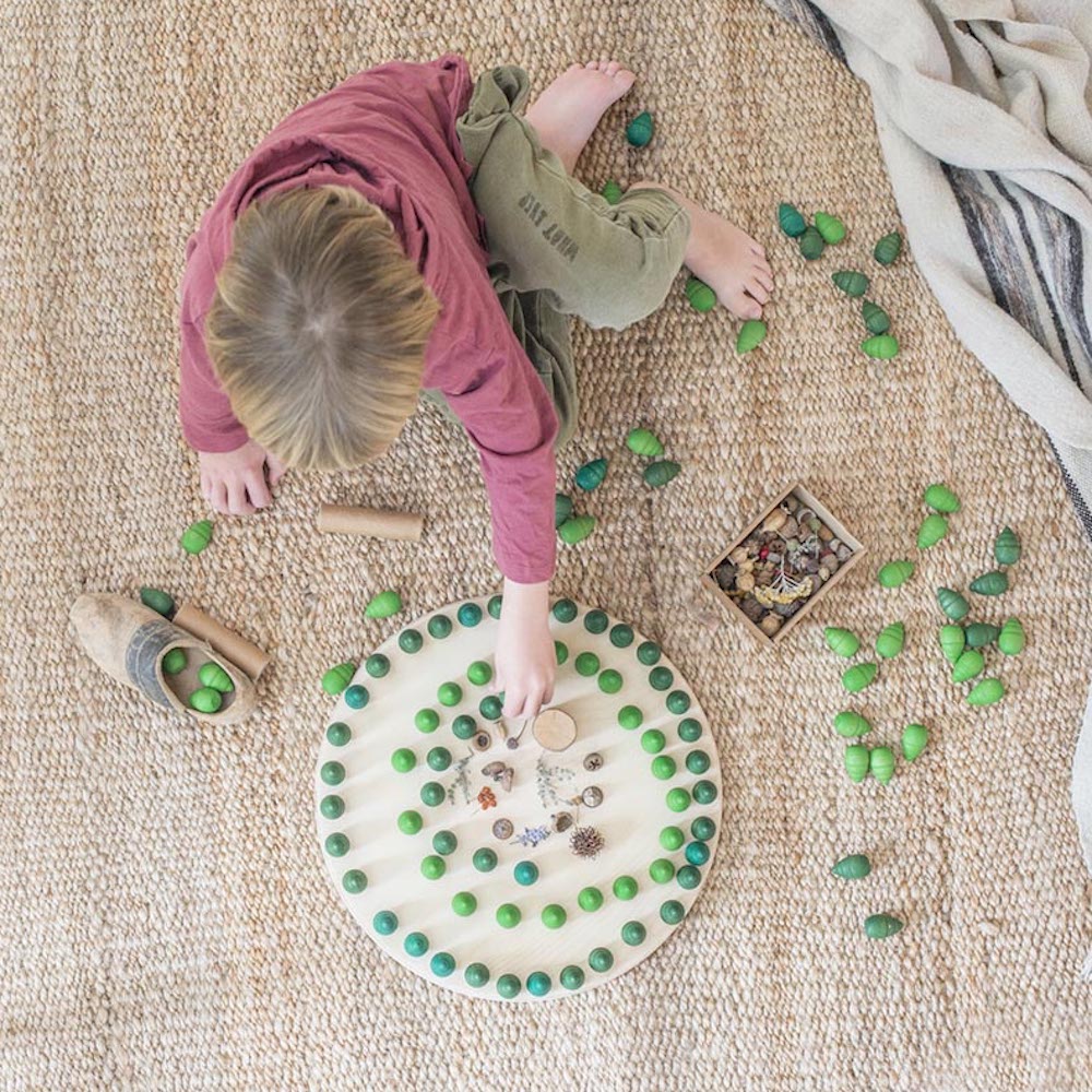 Child playing with green objects on a textured floor