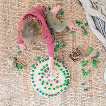 Child playing with green objects on a textured floor