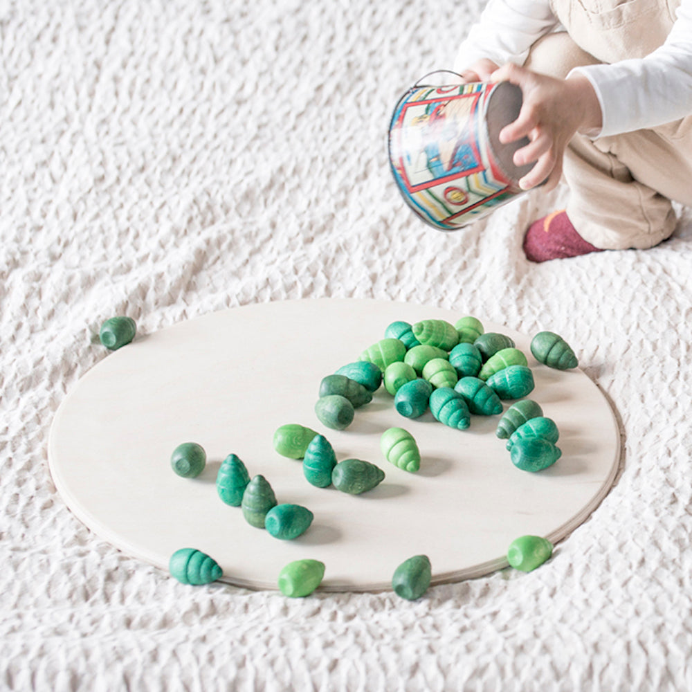 Child playing with green toys on a white surface