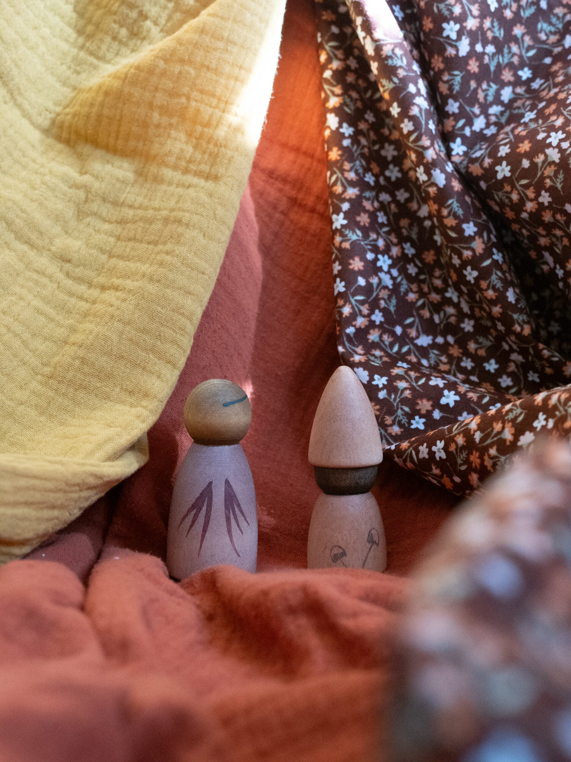 Two wooden pegs with natural finishes on a textured fabric background