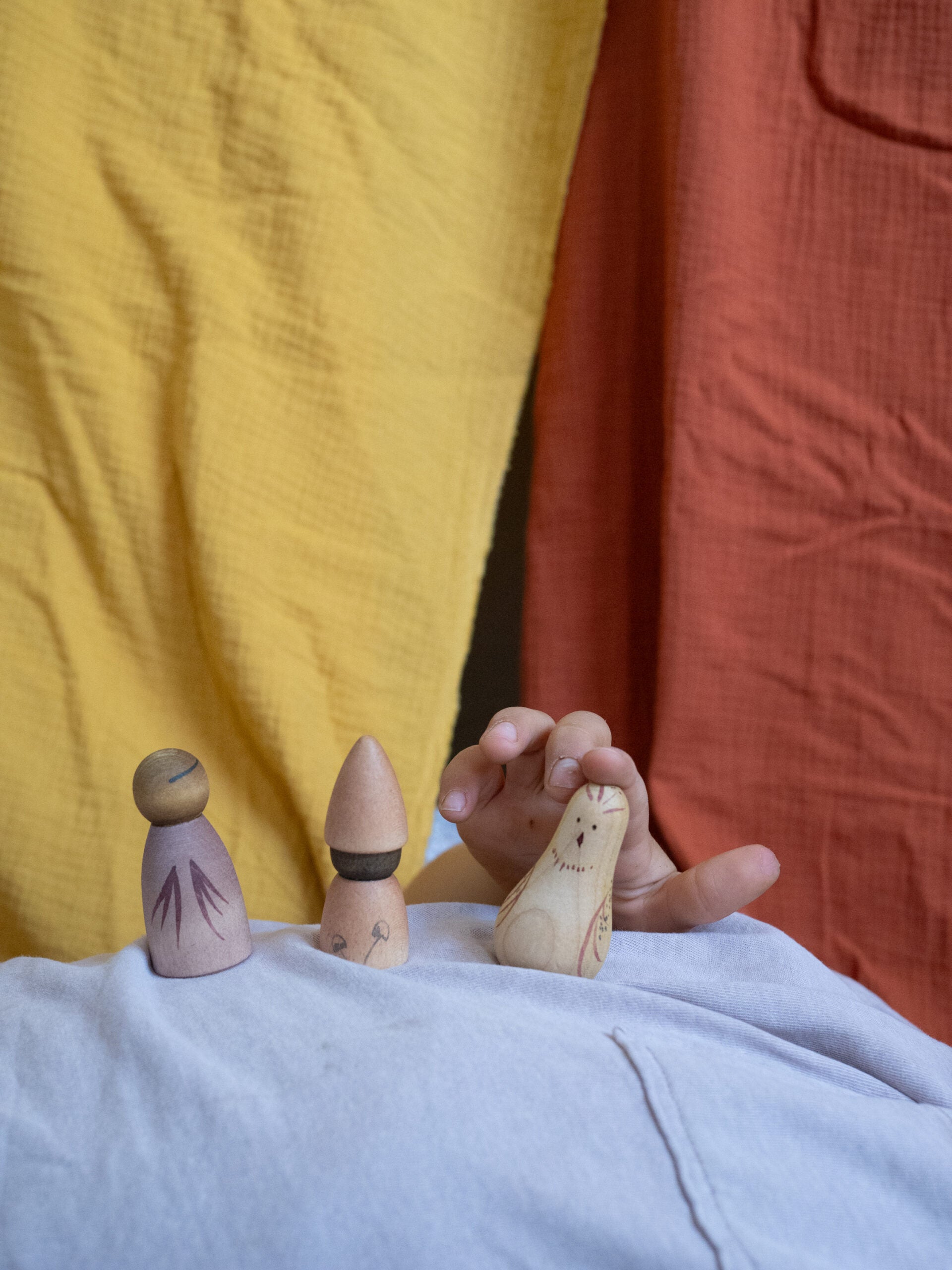 Three wooden peg dolls on a person's foot with a colorful background