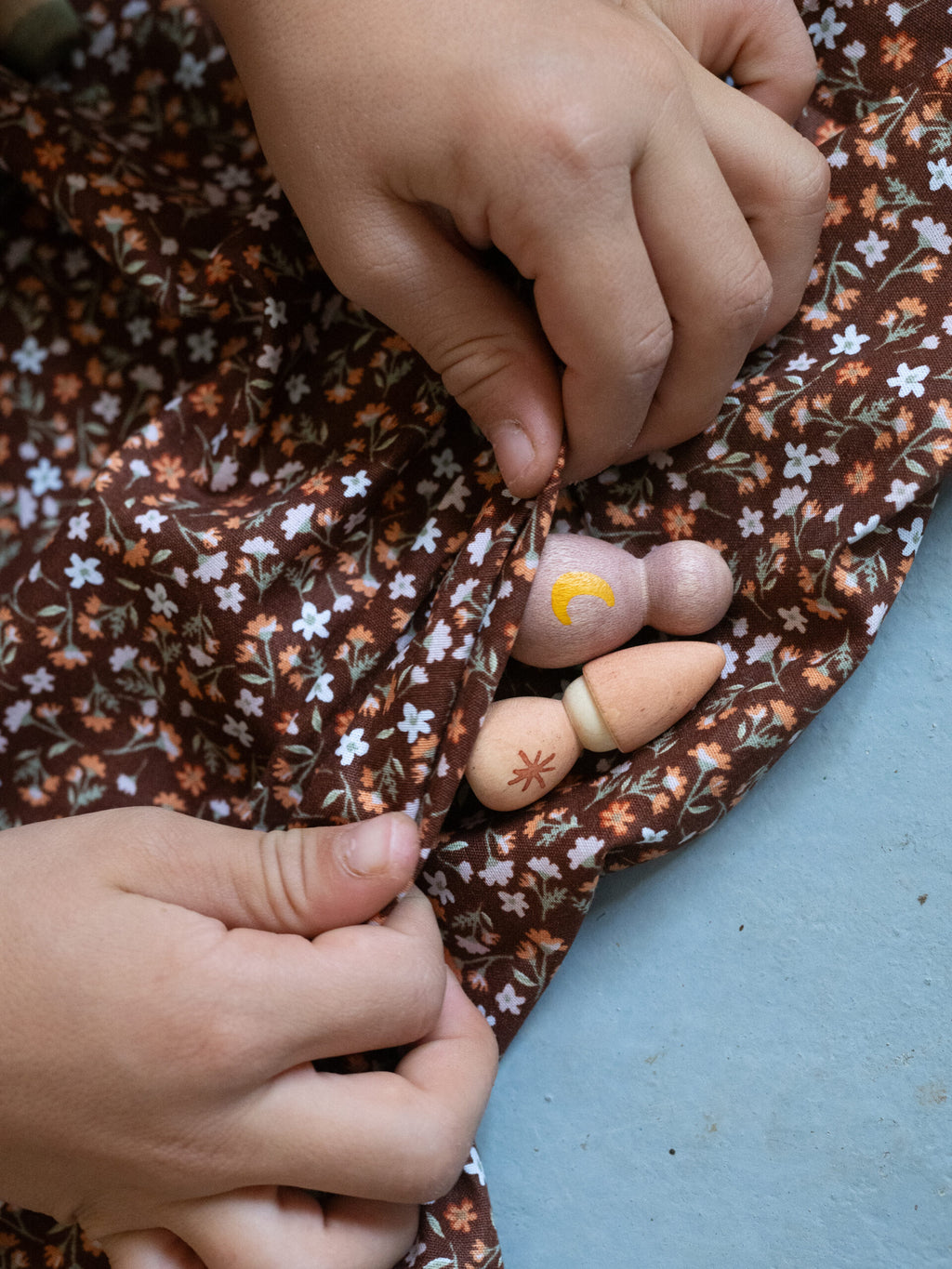Close-up of hands sewing a floral fabric with a blue background