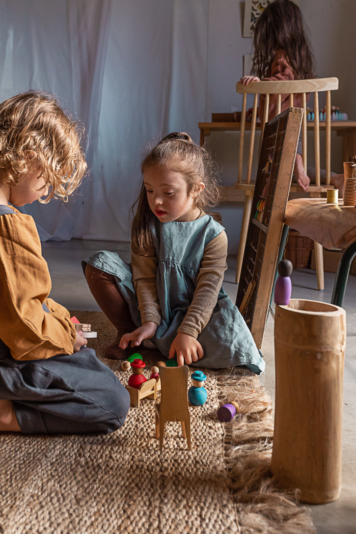 Two children playing with a wooden toy in a cozy room.
