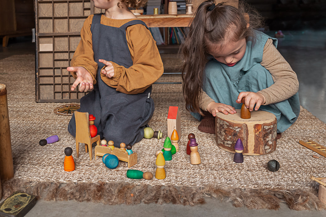 Two children playing with wooden toys on a carpeted floor.