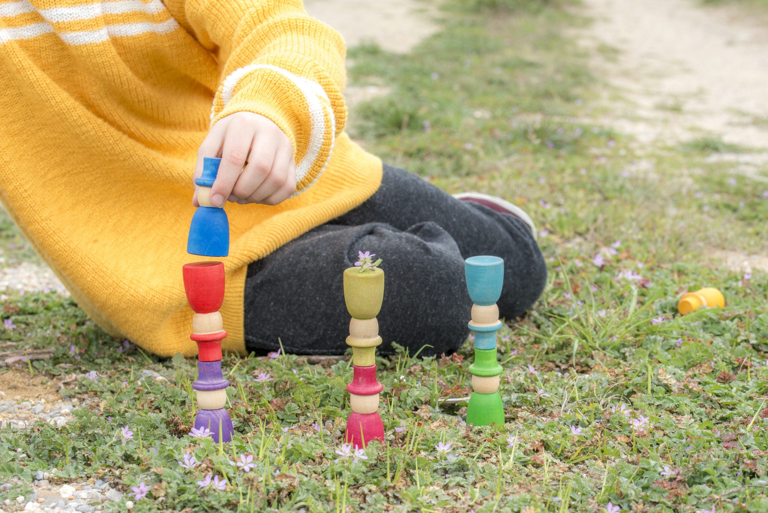 Child playing with colorful wooden toys on grass