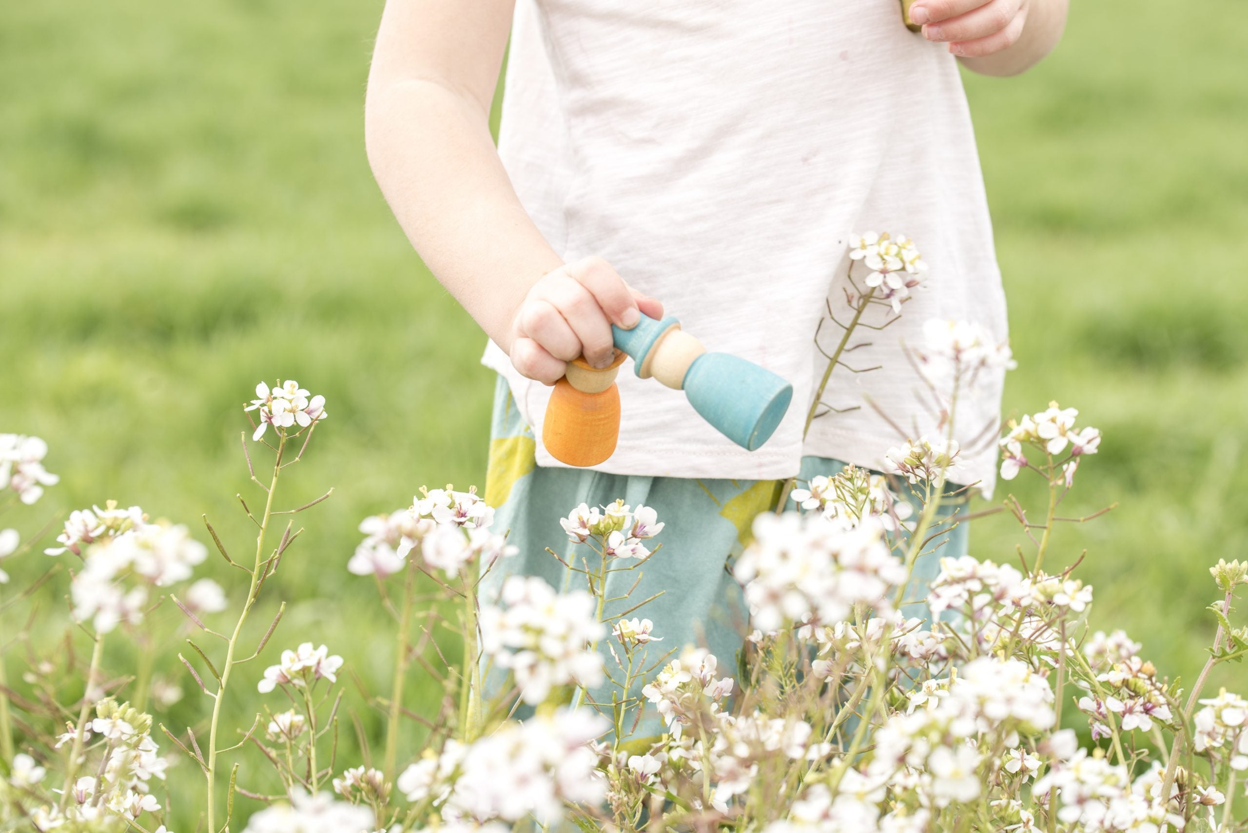 Child holding a colorful toy  in a field of white flowers