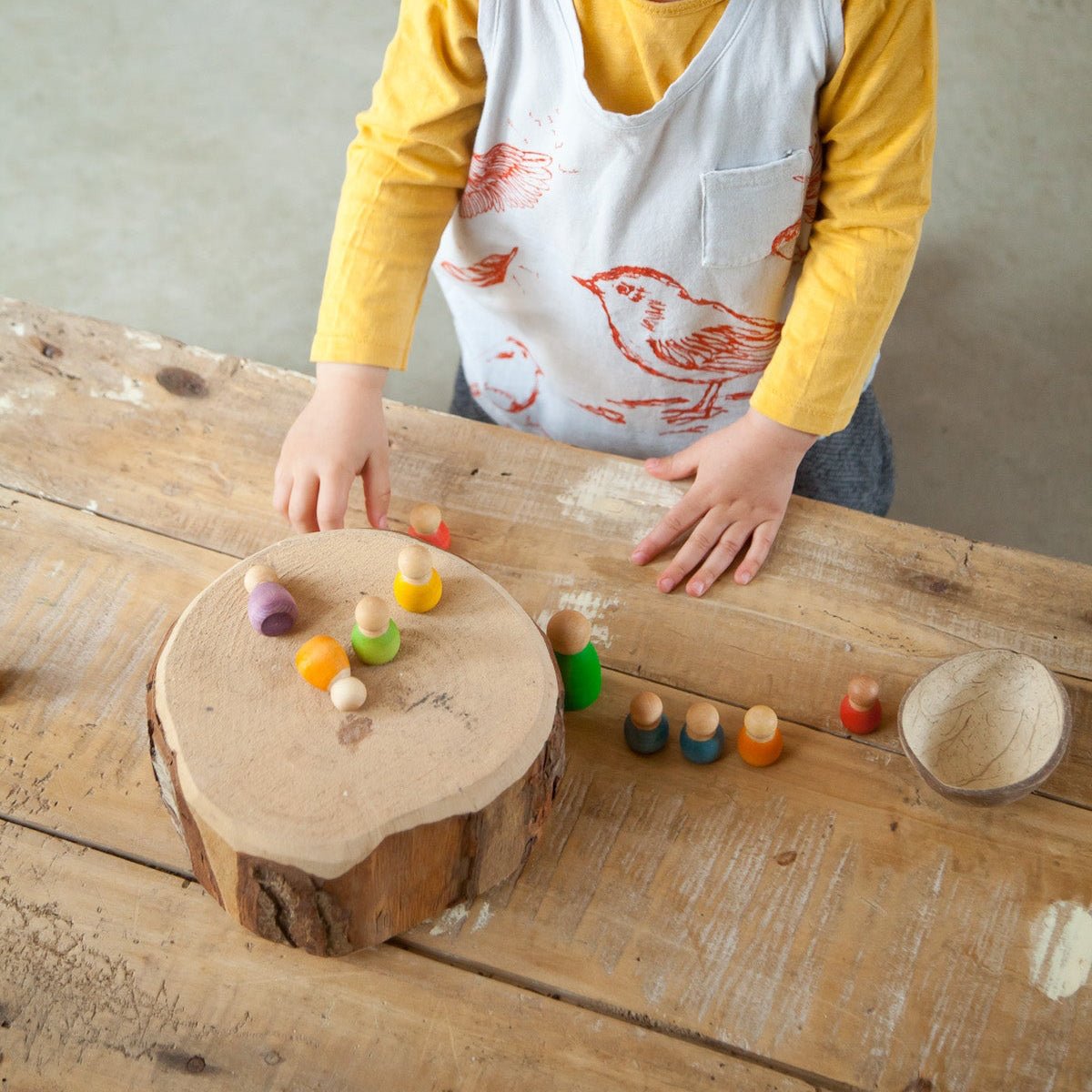 Child playing with colorful toys on a wooden surface