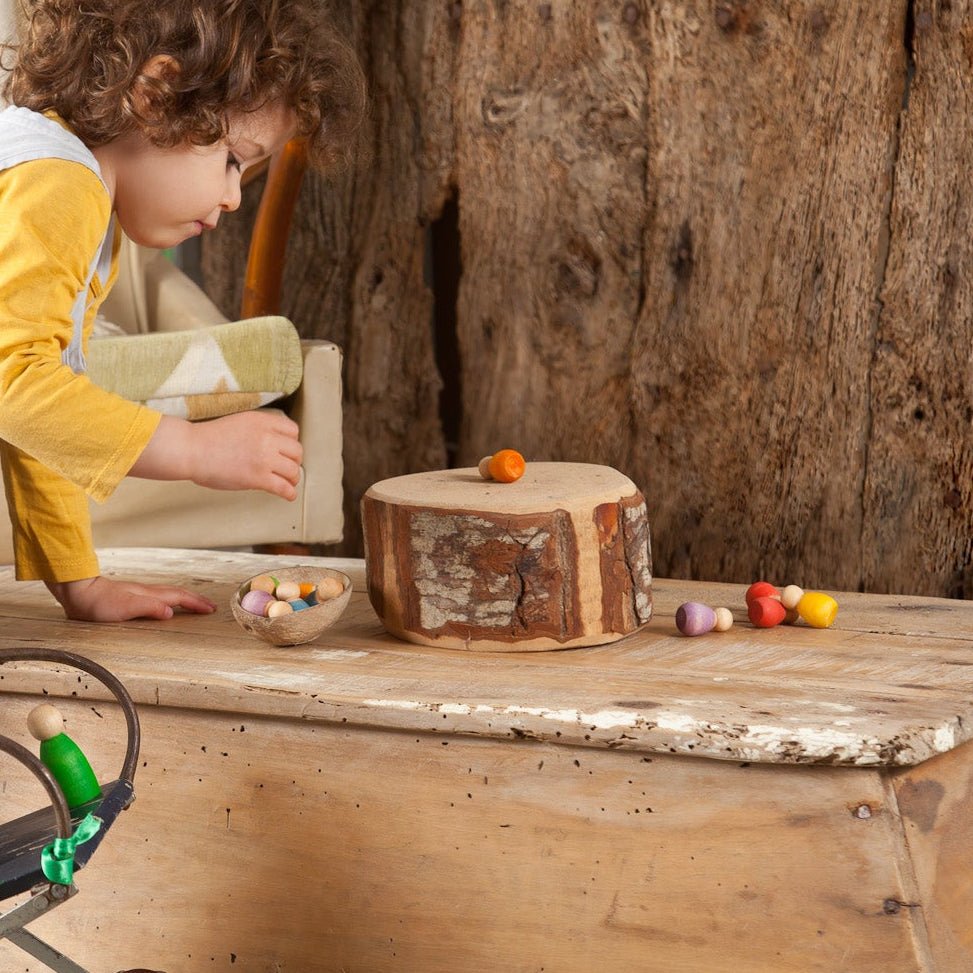 Child playing with toys on a wooden table in a rustic setting