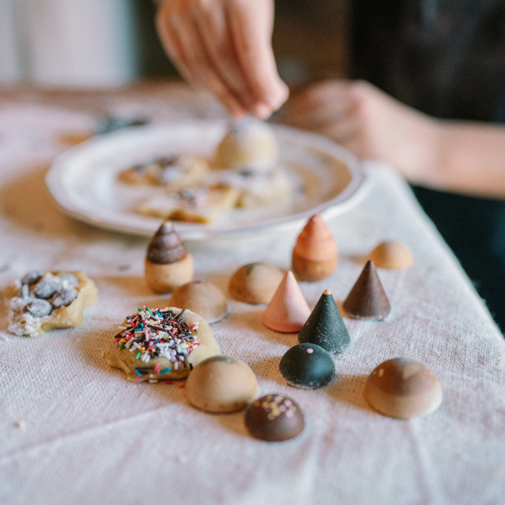 Children's hands arranging small cookies on a tablecloth.