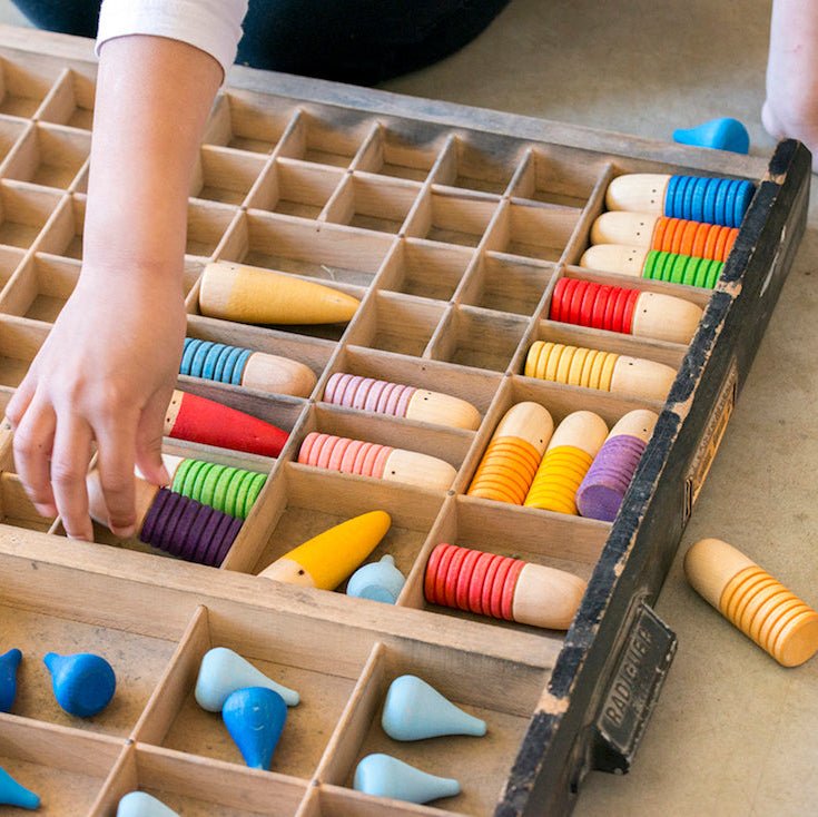 Children playing with a wooden abacus and colorful beads on a table.