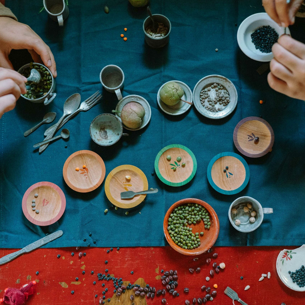 Two people preparing food on a table with various ingredients and utensils.