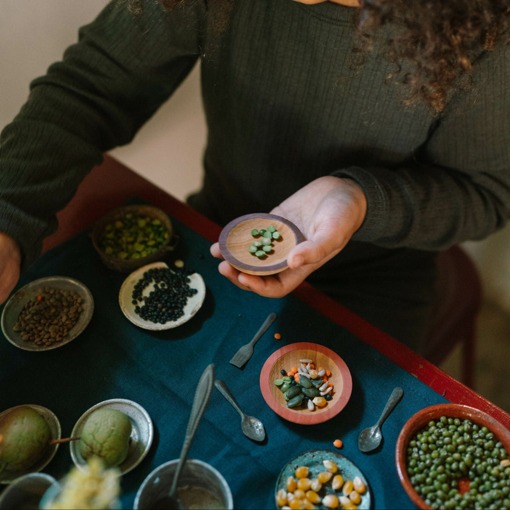 Person holding a small container with food on a table with various dishes.