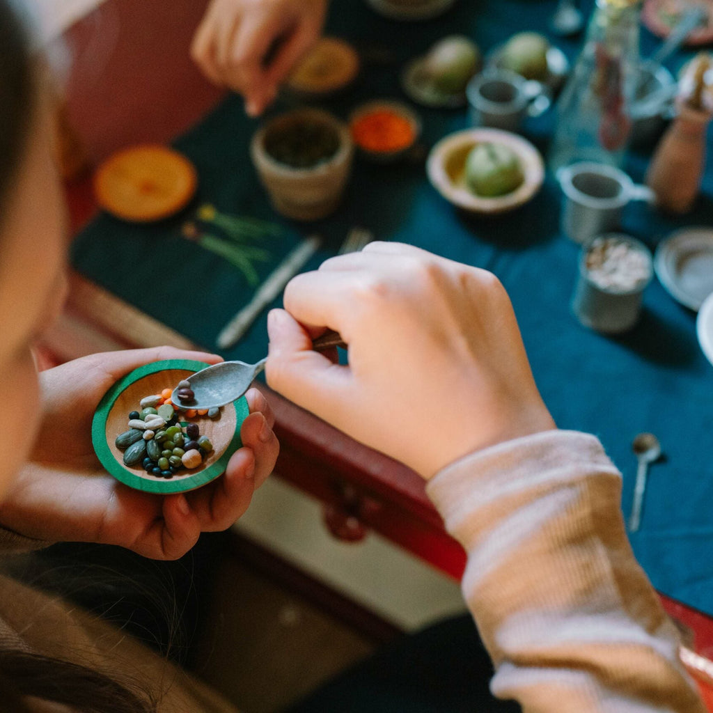 Two people working with small containers on a table filled with various items.