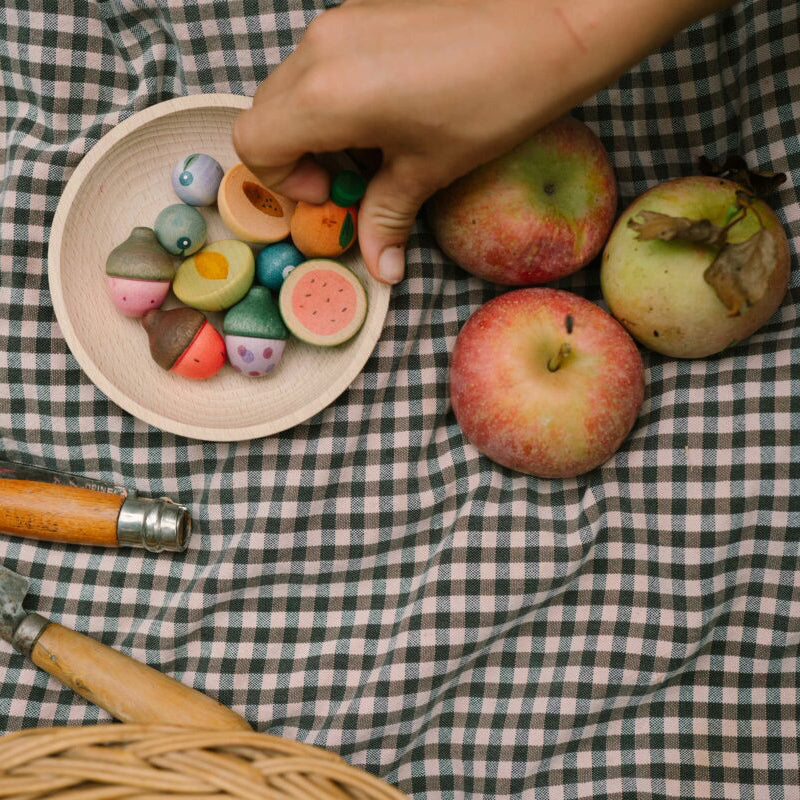 Colorful candies on a plate with apples and a knife on a checkered tablecloth