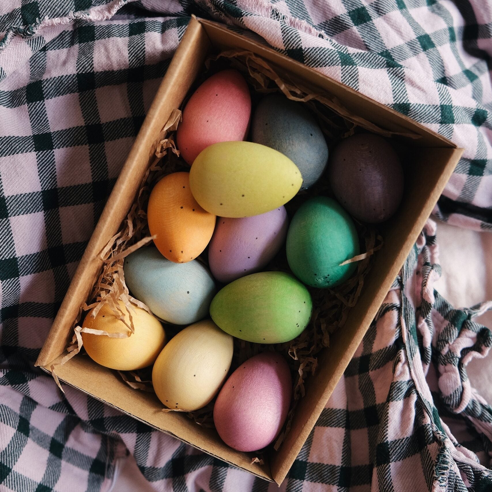Box of colorful Easter eggs on a checkered fabric background