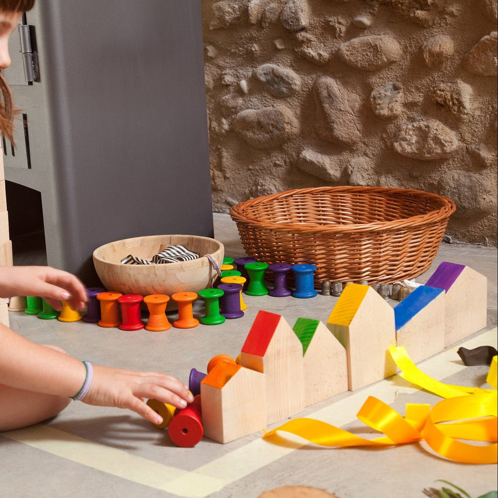 Child playing with colorful wooden toys on a stone floor.