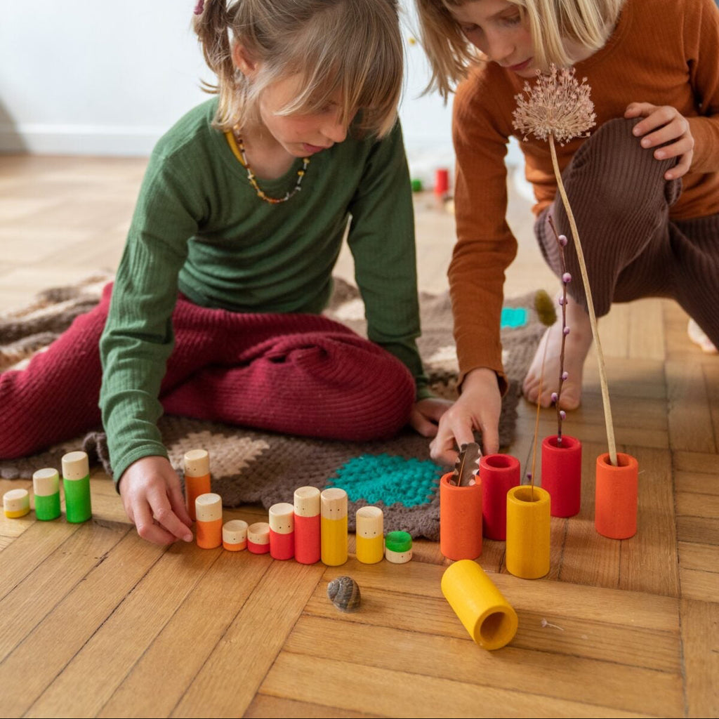 Two children playing with colorful toys on a wooden floor.