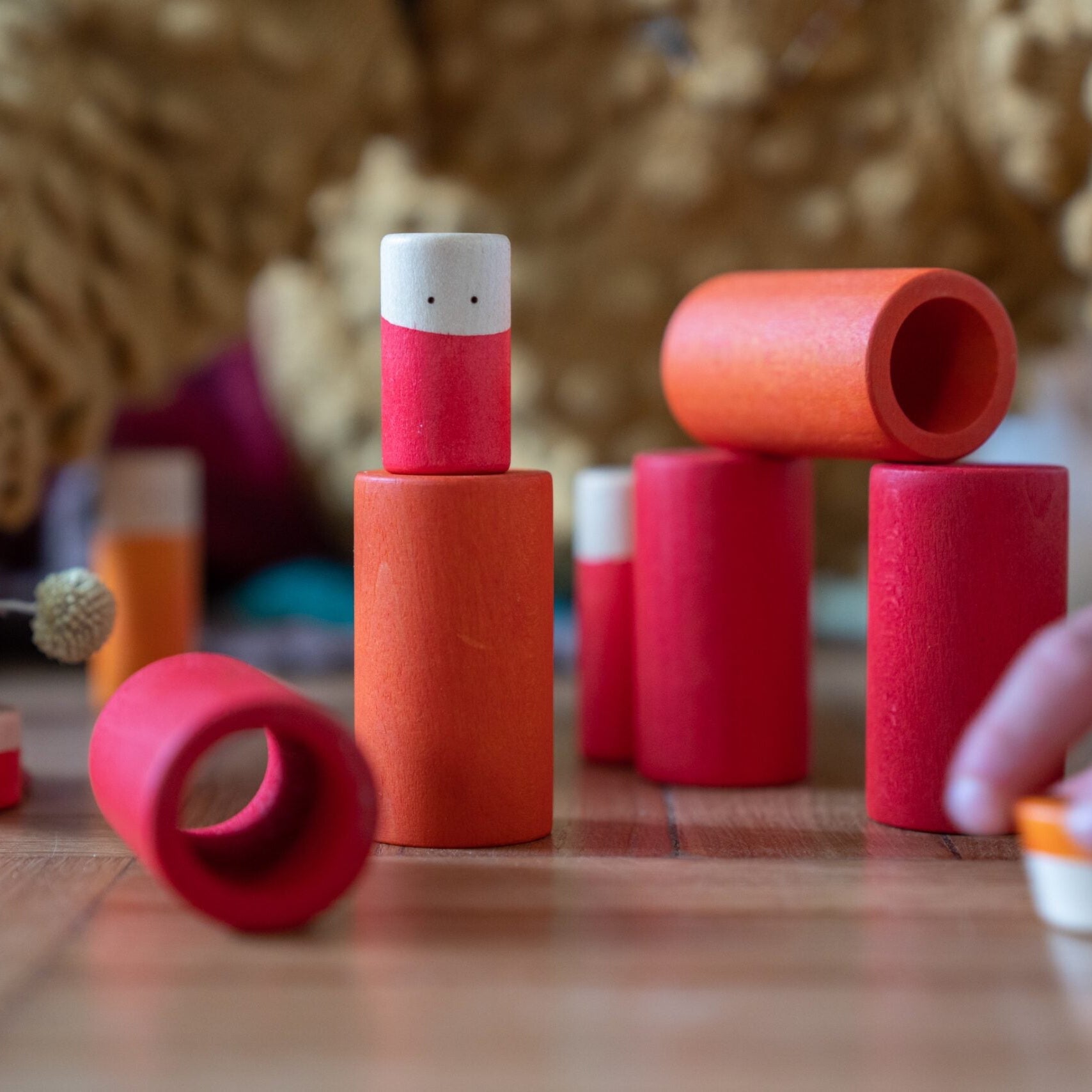 Children playing with red cylindrical toys on a wooden surface