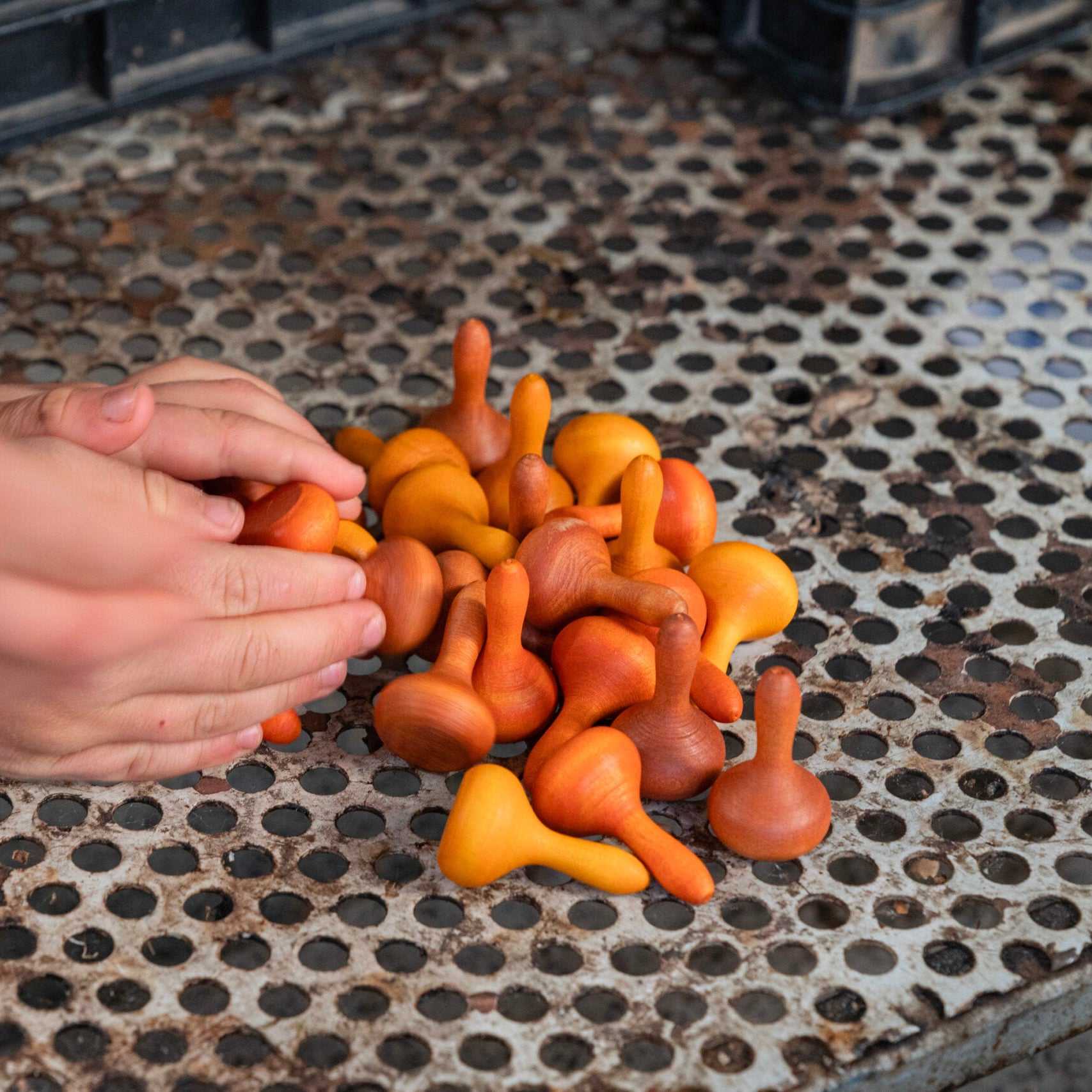 Colorful plastic toys on a textured metal surface with hands interacting.