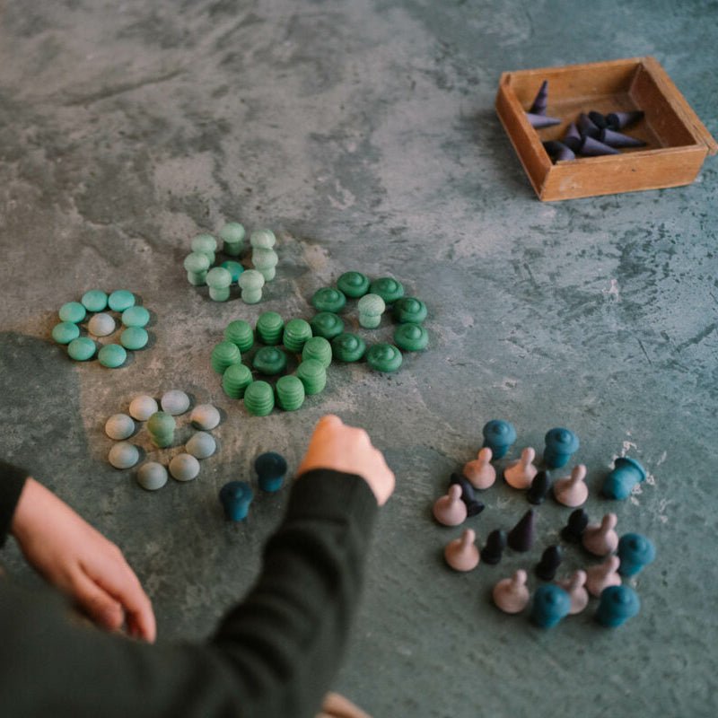 Person arranging small figurines on a textured surface