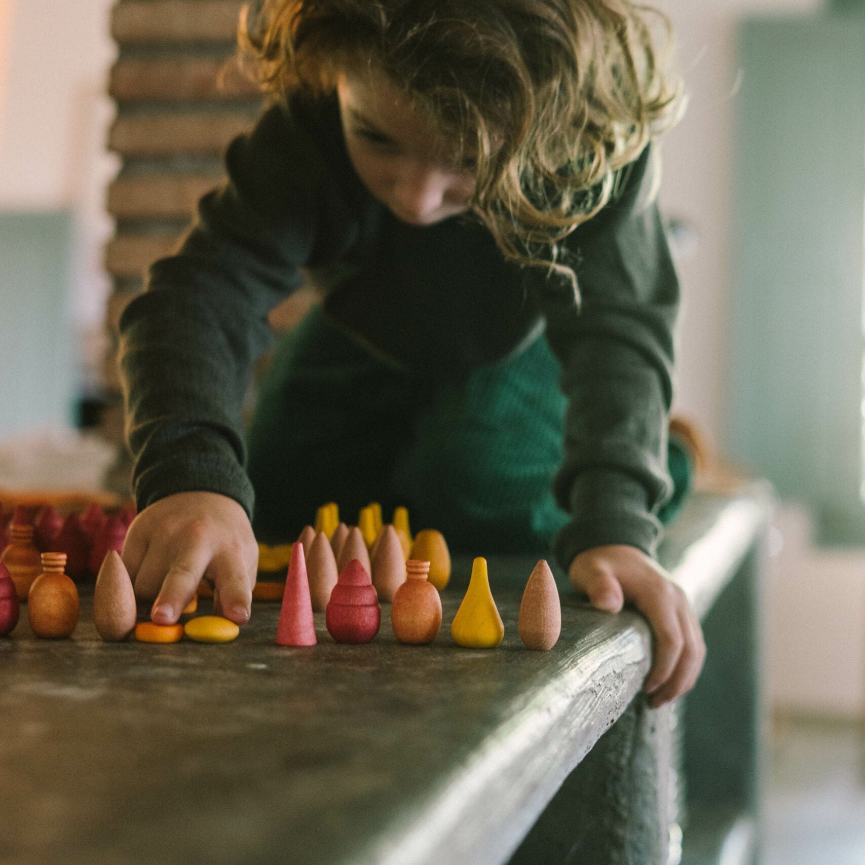 Child playing with colorful wooden toys on a table.