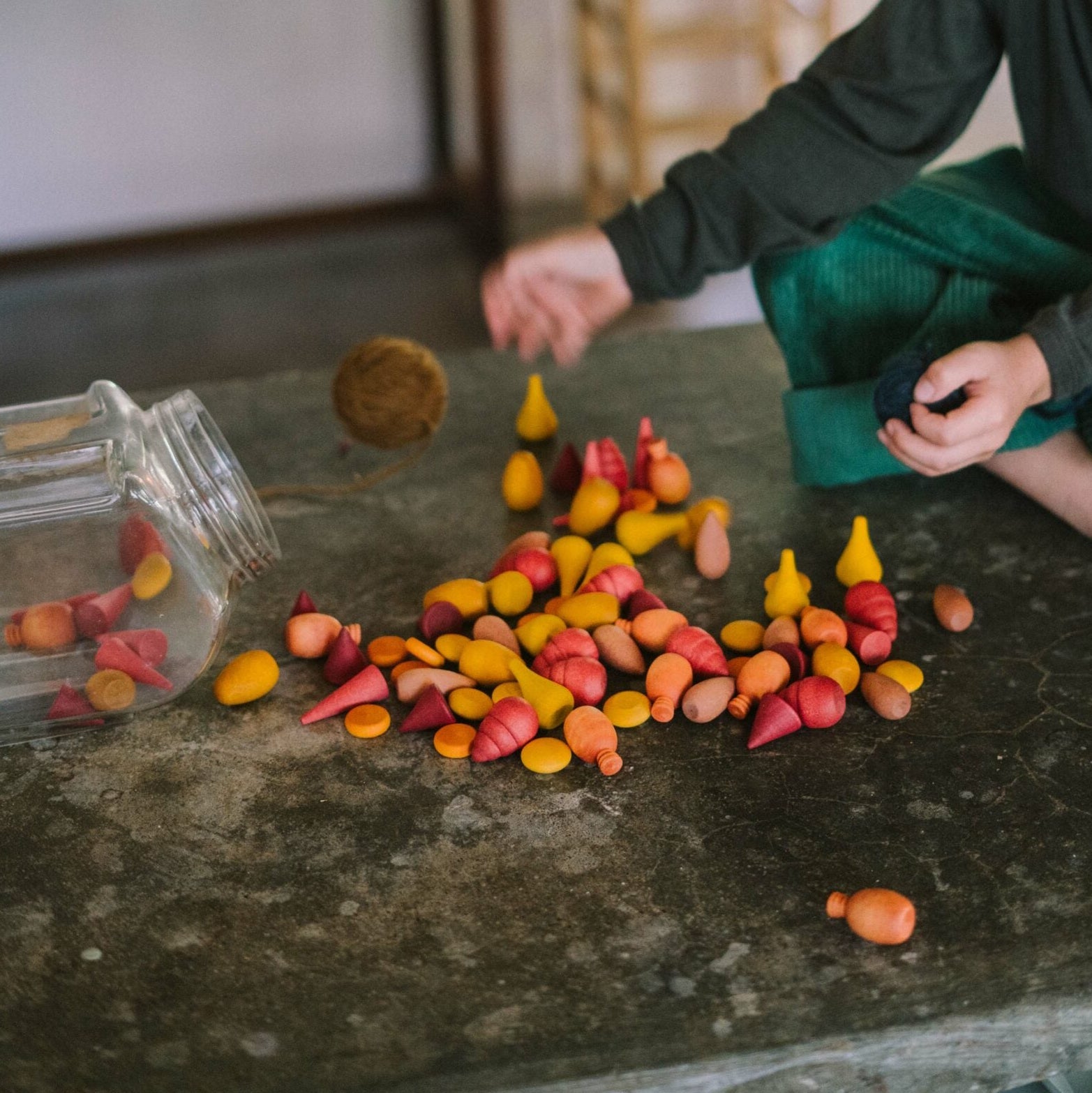 Child playing with colorful candies on a table in a home setting