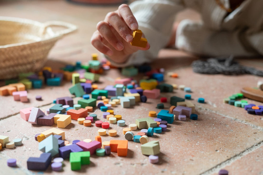 Child playing with colorful wooden blocks on a wooden floor.