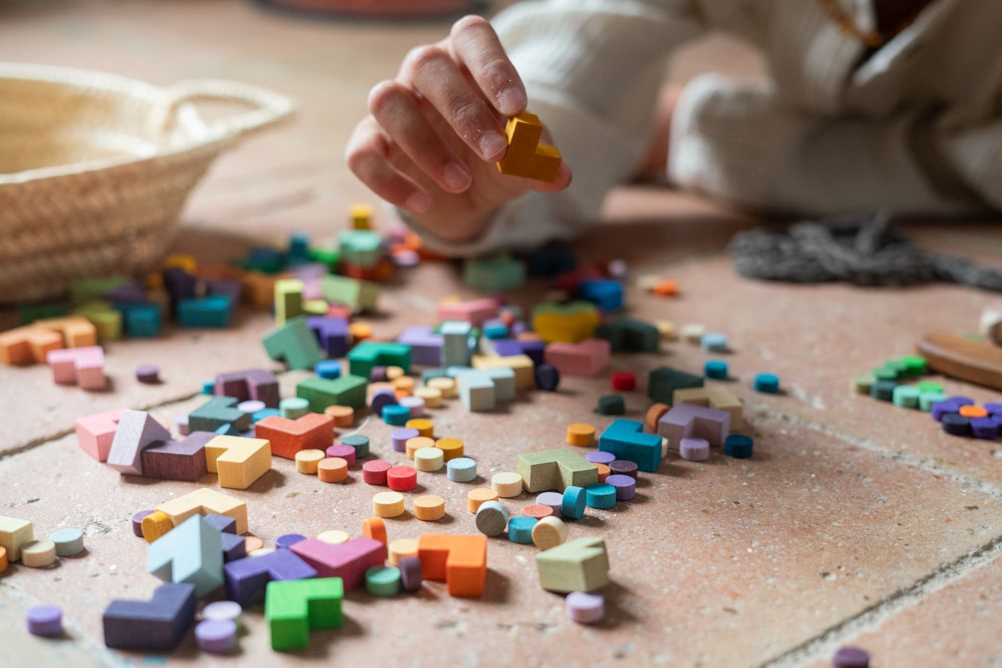 Child playing with colorful wooden blocks on a wooden floor.