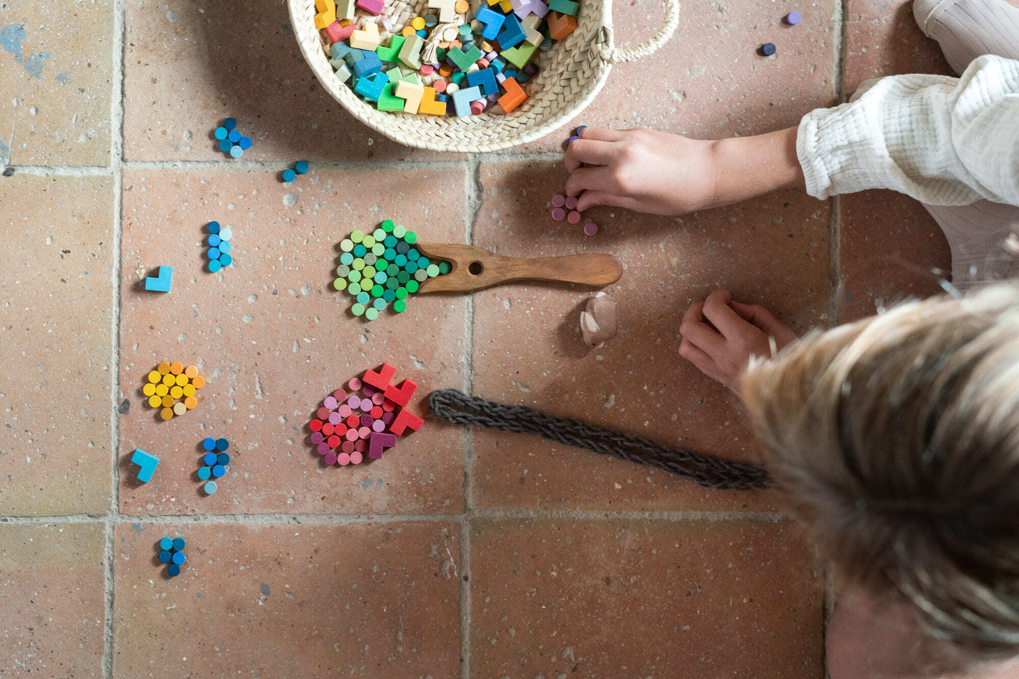 Child playing with colorful toys on a tiled floor