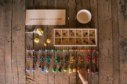 Color sorting activity on a wooden table with various colored objects and tools.