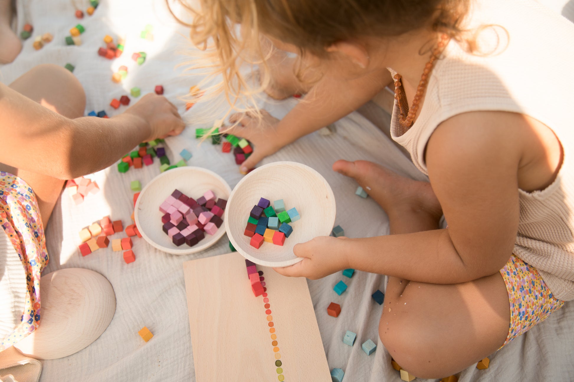 Two children playing with colorful blocks on a blanket