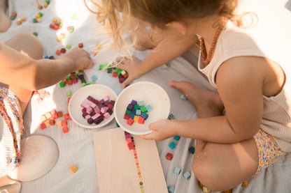 Two children playing with colorful blocks on a blanket