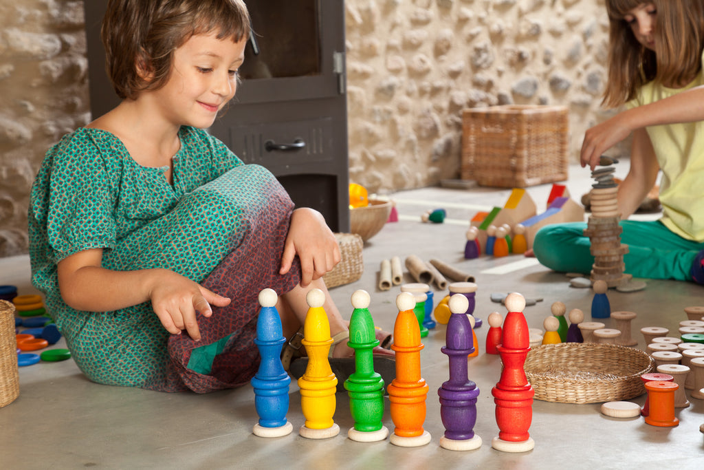 Child playing with colorful wooden toys on a stone floor.