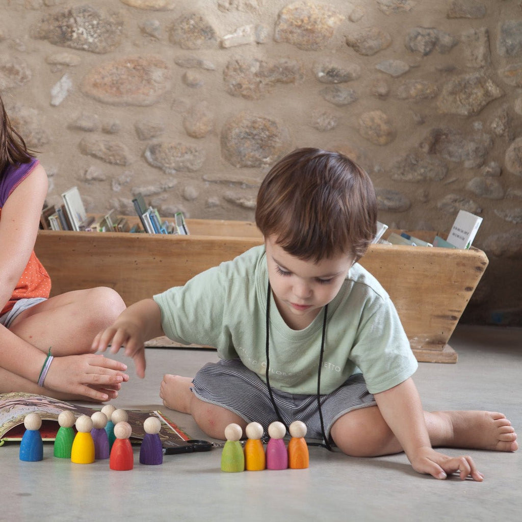 Two children playing with colorful wooden toys on a stone floor.