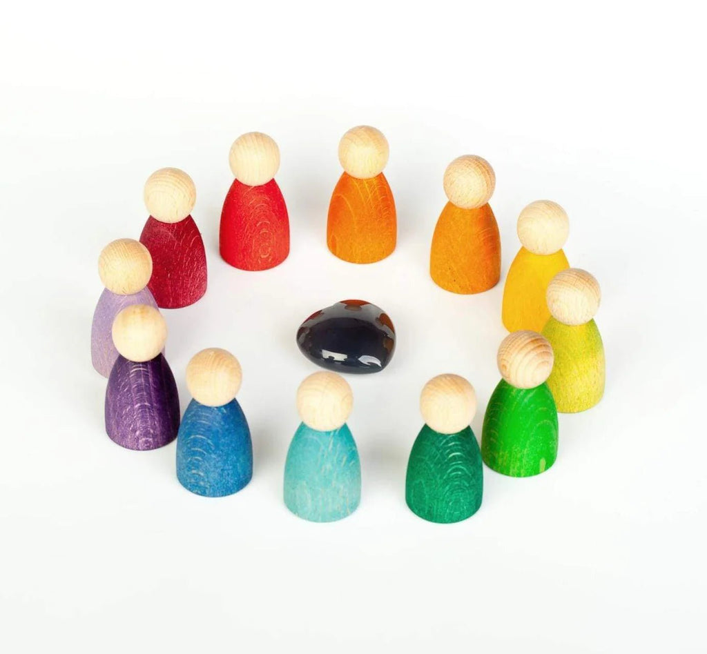 Set of colorful wooden peg people with a black rock on a white background