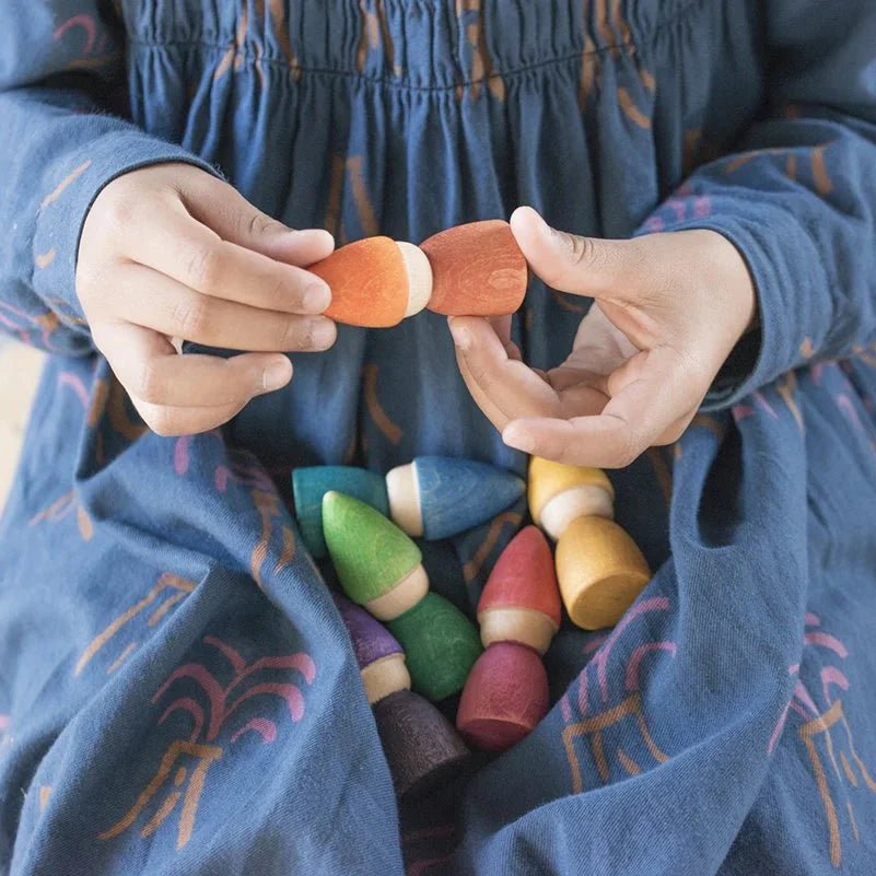 Child holding colorful wooden toys in a blue dress with patterns.
