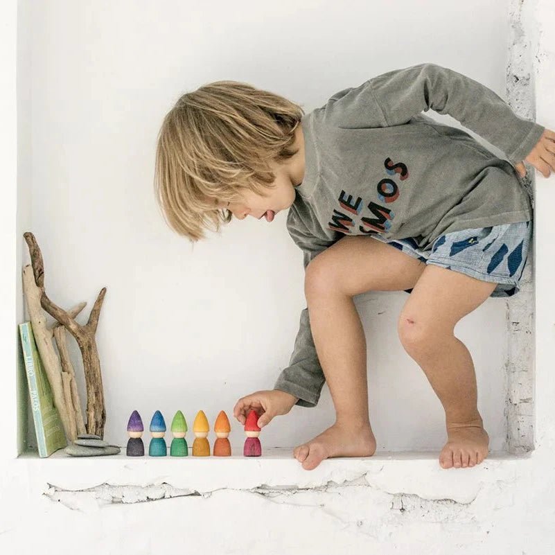 Child playing with colorful wooden toys on a white surface
