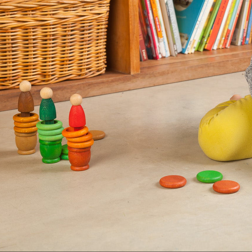 Child playing with colorful toys on the floor in a room with bookshelves and plants.