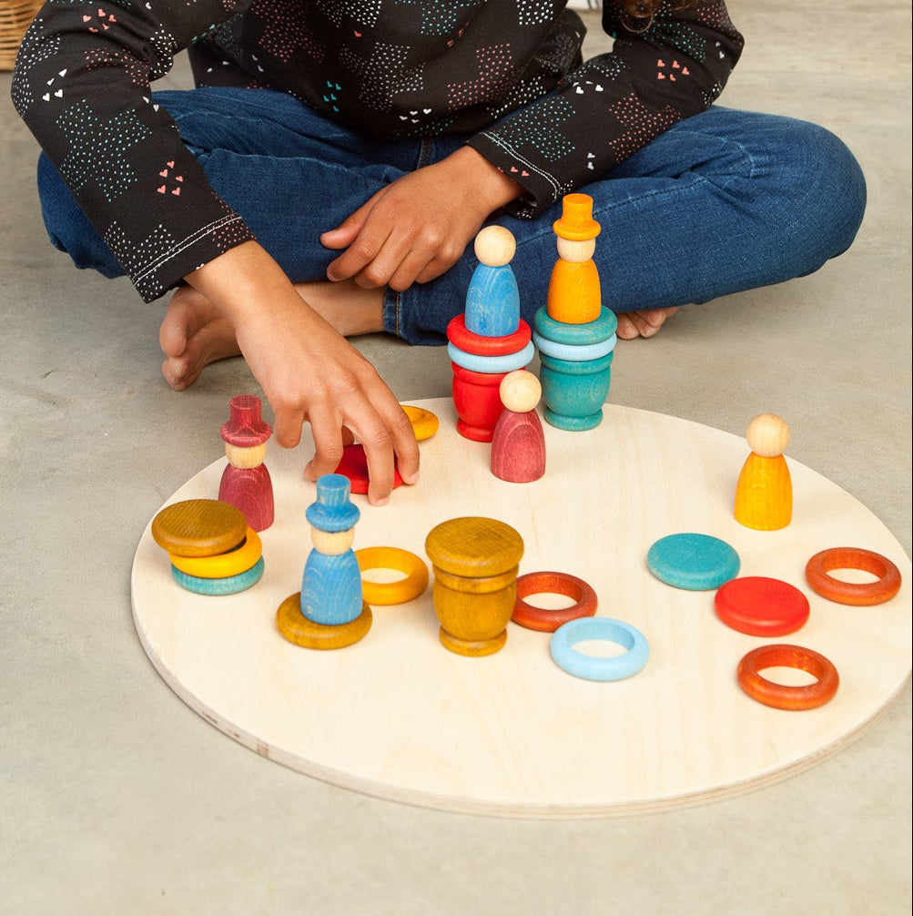 Child playing with colorful toys on a concrete floor.